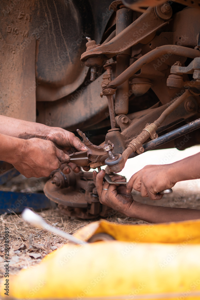 Hands of mechanic fixing wishbone control arm of the truck part to repair front wheel Hands of mechanic fixing wishbone control arm of the truck part to repair front wheel