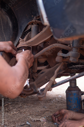Hands of mechanic fixing wishbone control arm of the truck part to repair front wheel