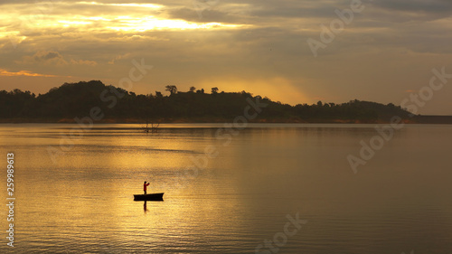 Silhouette of a fishing people on the boat in the middle of the water in the beautiful morning light © isarescheewin