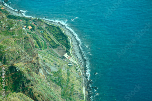 Top view of the coast of the island of Madeira with a coastline and areas with planted plants. Cropped shot, top view, free space for text, horizontal. The concept of nature and agriculture.