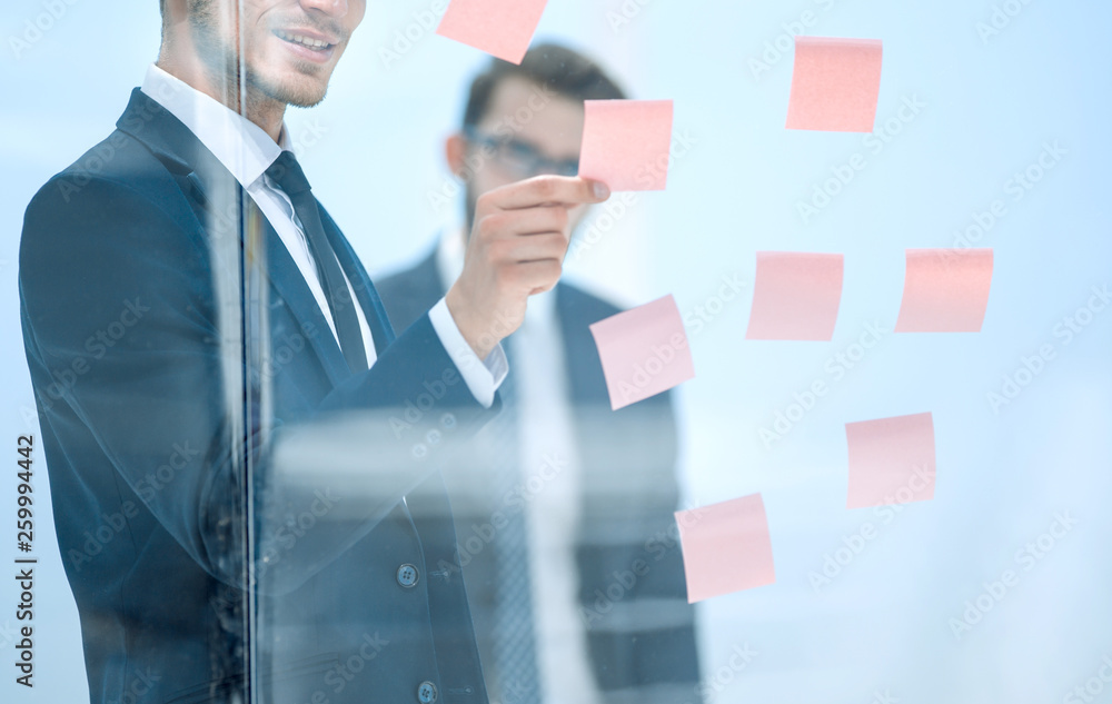 serious employee reads a sticker-note on the office Board. serious employee reads a sticker-note on the office Board.