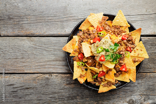 Corn chips nachos with fried minced meat and guacamole on wooden background. photo