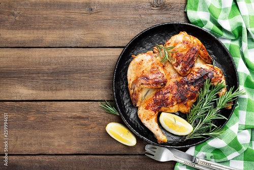 Grilled chicken Tabaka with sauce on wooden background.