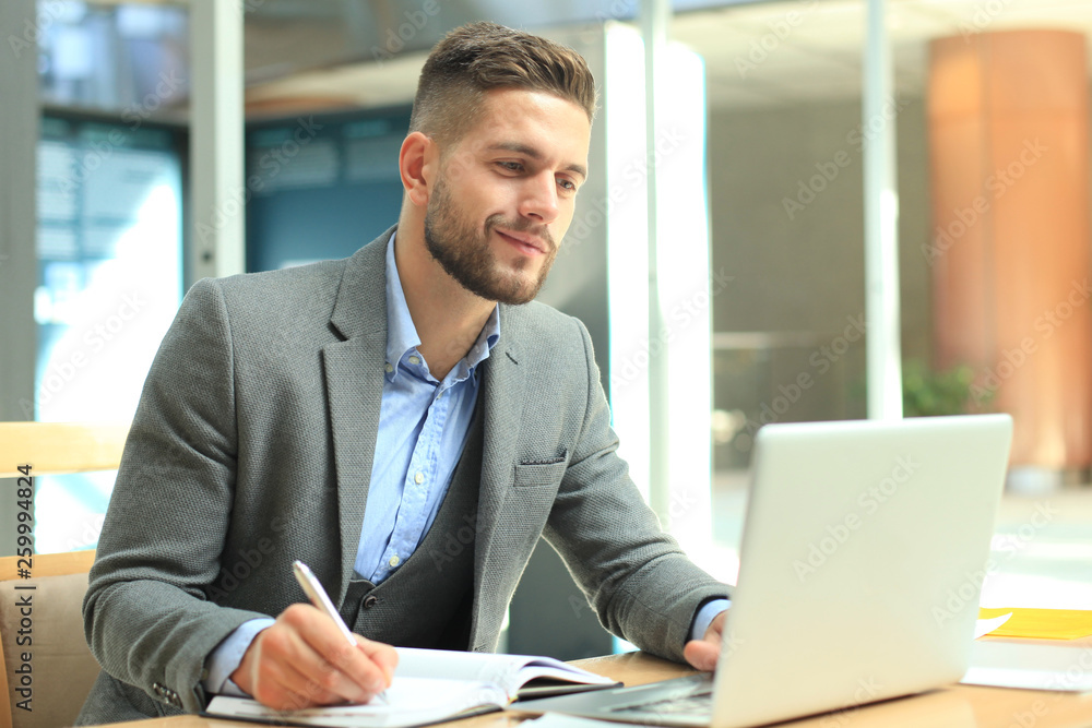 Portrait of young man sitting at his desk in the office. Portrait of young man sitting at his desk in the office.