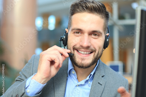 Smiling friendly handsome young male call centre operator.