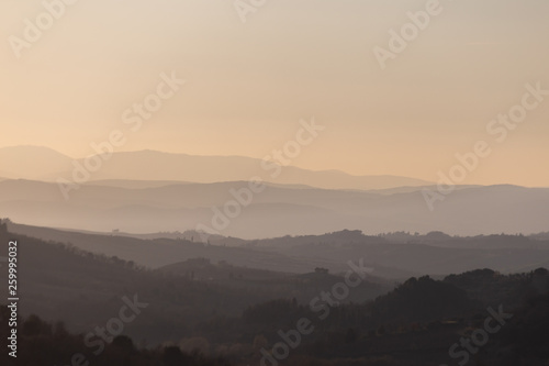 Beautiful view of Tuscany hills at sunset, with mist and warm colors