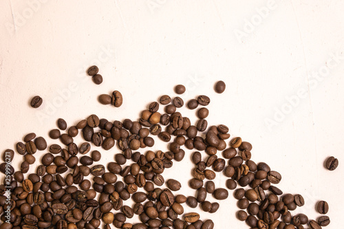 Roasted coffee beans in bulk on a light pink background. dark cofee roasted grain flavor aroma cafe, natural coffe shop background, top view from above, copy space