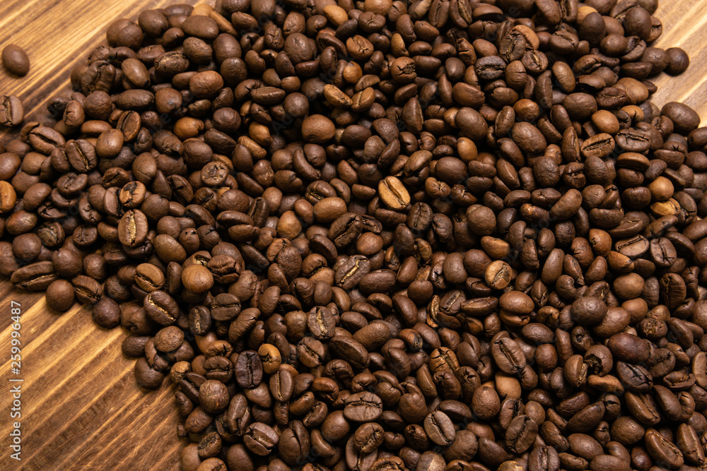 Roasted coffee beans in bulk on a wooden background Roasted coffee beans in bulk on a wooden background
