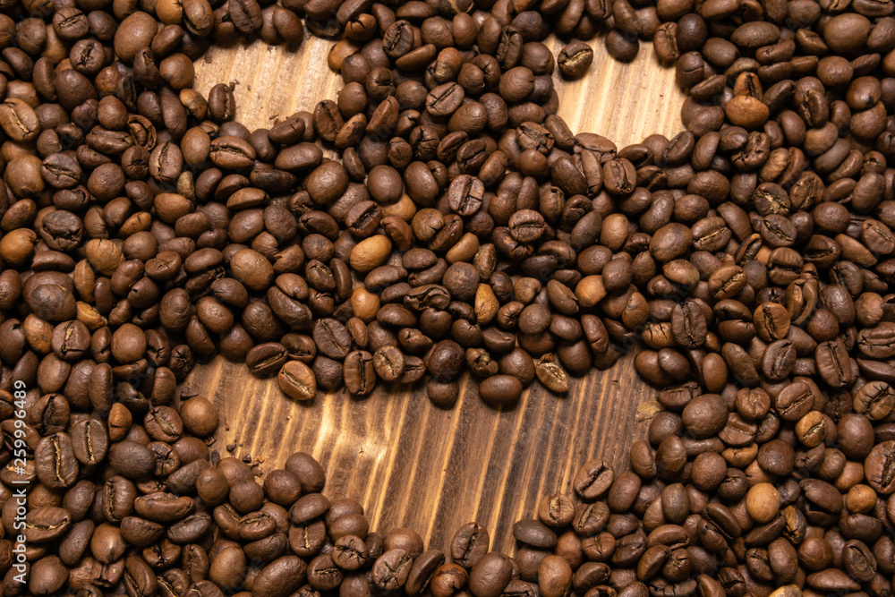 Roasted coffee beans in the form of a smiling face on a wooden background Roasted coffee beans in the form of a smiling face on a wooden background