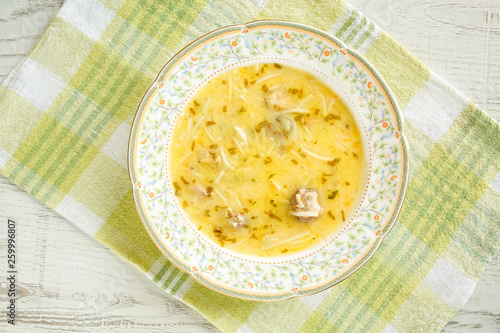 Top view of a traditional bulgarian chicken soup dish (pileshka chorba), thickened with egg on a green napkin on a white wooden table photo