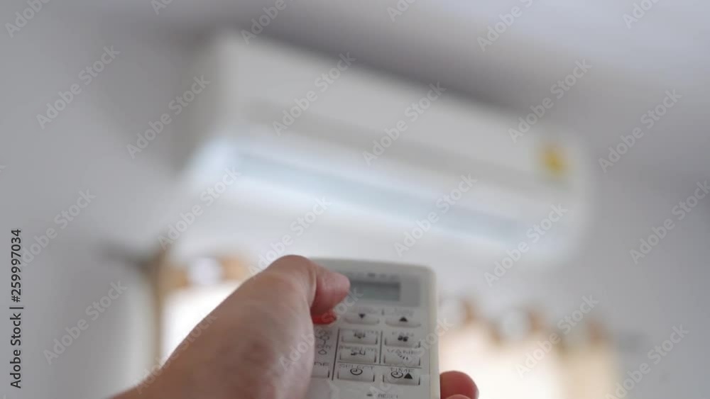 Hand using remote control closing air conditioner in bedroom in the morning. Saving energy Hand using remote control closing air conditioner in bedroom in the morning. Saving energy
