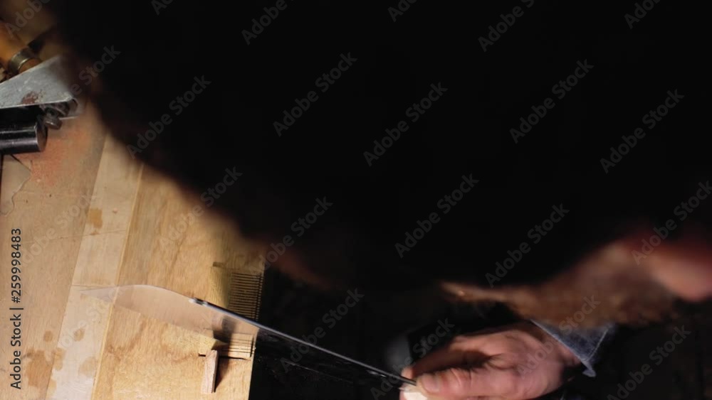 a carpenter craftsman makes a cut on a wooden beard comb using a handsaw. view from above. 4 k a carpenter craftsman makes a cut on a wooden beard comb using a handsaw. view from above. 4 k