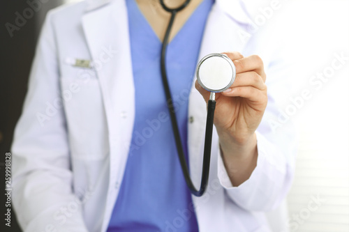 Unknown doctor woman holds stethoscope head, close-up. Physician ready to examine and help patient. Helping and insurance in health care, best treatment and medicine concept