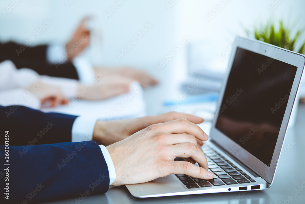 Group of business people working together in office. Man hands typing on laptop computer Group of business people working together in office. Man hands typing on laptop computer