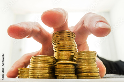 A man's hand is hanging over gold coins and wants to pick them up. Business concept