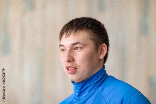 young man in blue sports jumper on wall background
