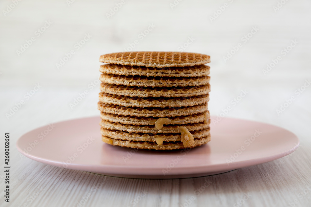 Stack of sweet Dutch stroopwafels with honey-caramel filling on pink plate, side view. Close up. Stack of sweet Dutch stroopwafels with honey-caramel filling on pink plate, side view. Close up.