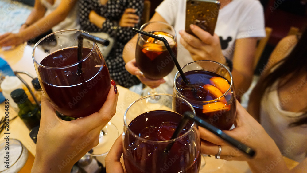 People drink a cocktail. Alcohol. Club. Cheerful company in the bar holds glasses with red sangria. Holiday in spain concept