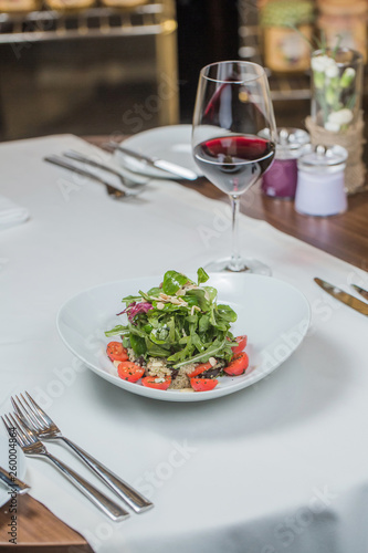 Salad of vegetables with a glass of red wine, vegetarian salad, restaurant dish, a reserved table.