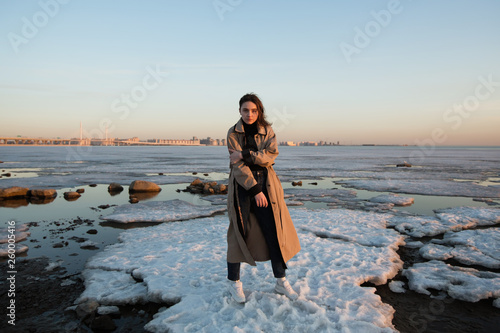 Full-length portrait of the beautiful girl. Photo shoot near river at winter.