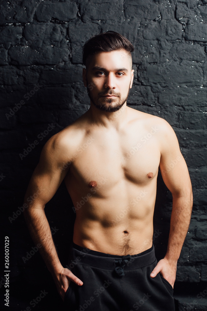 Studio shot of young handsome man shirtless against black background