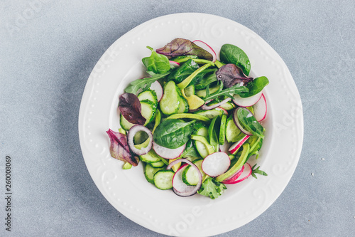 Healthy salad with radishes, avacado, cucumbers, spinach and ir rocket salad in a plate top view