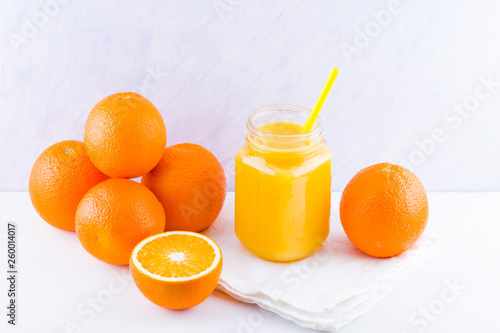 Orange fruits and juice on white background. Citrus fruit for making juice with manual juicer. Oranges on white napkin. Mason jar with orange juice