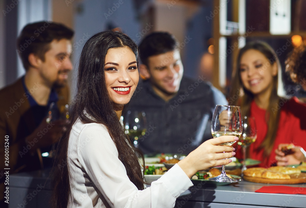 Woman with a glass against the background of friends in a restaurant. Woman with a glass against the background of friends in a restaurant.