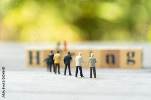Miniature people, candidates and wooden word block "HIRING". Human resource concept, recruiting, hiring process.