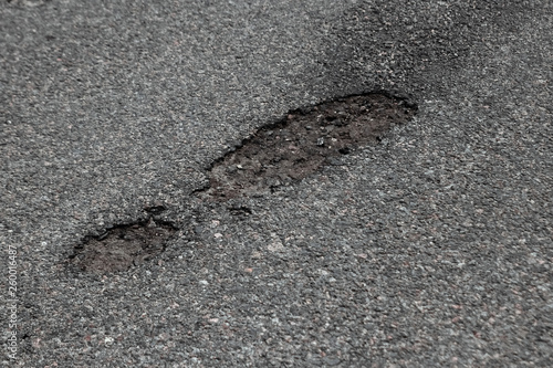 The road in disrepair with a lot of potholes. Cars go with the risk of breakdowns.