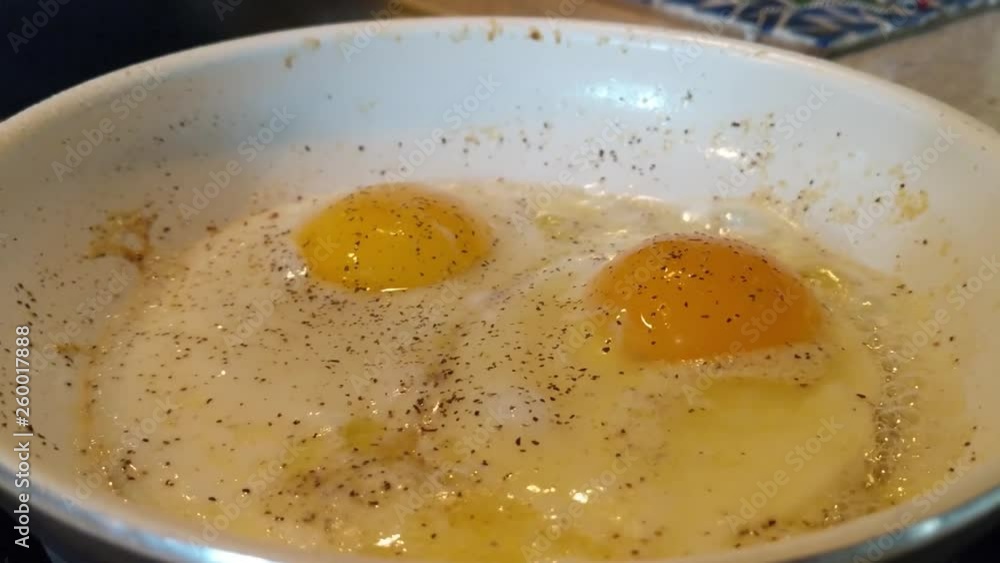 Two eggs frying in butter with salt and pepper Two eggs frying in butter with salt and pepper