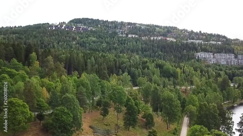 a brief pan of some houses built into a green wodded hill in norway photo