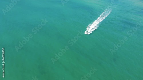 Drone flying over a jetski leaving the beach near Abel Tasman National Park in New Zealand with beautiful sand bars, coastal forests and jagged rocks. photo