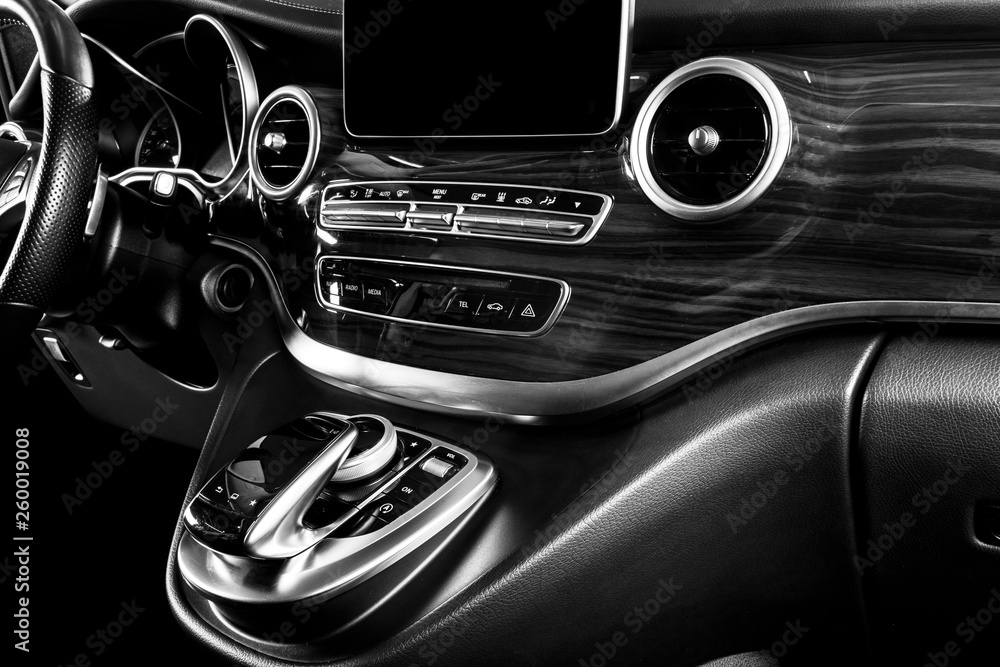 Modern Luxury car inside. Interior of a car. Comfortable leather seats. Perforated leather cockpit with white stitching. Steering wheel and dashboard. Automatic gear stick shift. Black and white