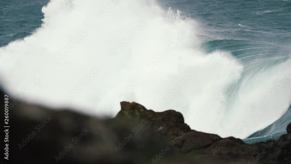 Locked off shot of large wave breaking onto rocks in slow motion. Locked off shot of large wave breaking onto rocks in slow motion.