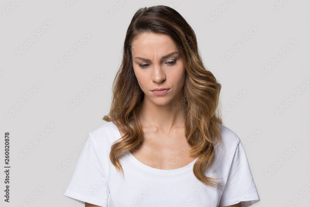Head shot portrait young attractive sad woman over grey background Head shot portrait young attractive sad woman over grey background