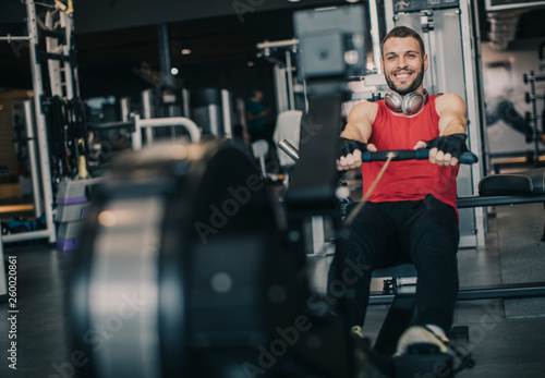 Young man doing workouts on a back with power exercise machine in a gym club © BGStock72