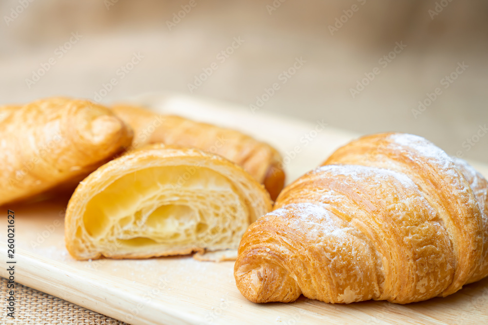Croissant with icing on wooden plate