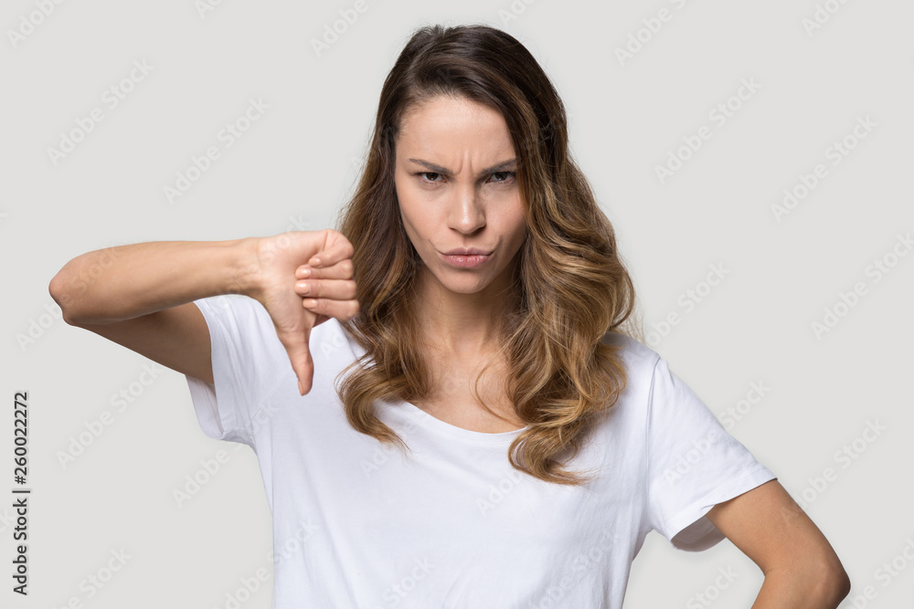 Angry woman showing thumb down disapproval gesture studio shot Angry woman showing thumb down disapproval gesture studio shot