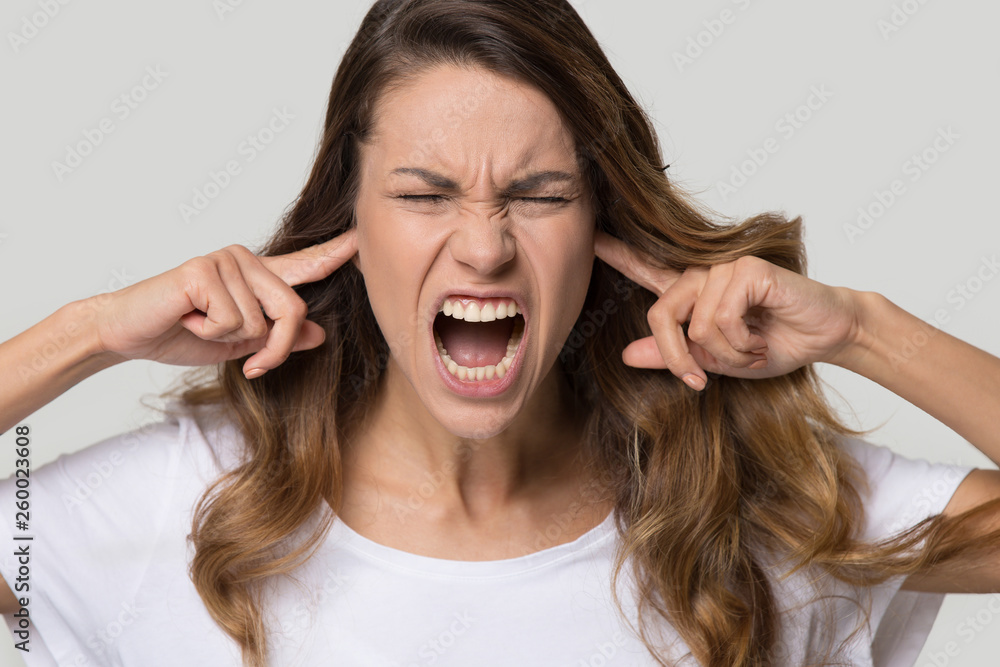 Close up portrait of screaming female close ears with fingers Close up portrait of screaming female close ears with fingers