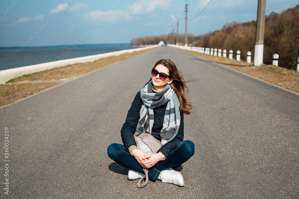 young beautiful girl sitting in the middle of the road, woman is resting outdoors young beautiful girl sitting in the middle of the road, woman is resting outdoors