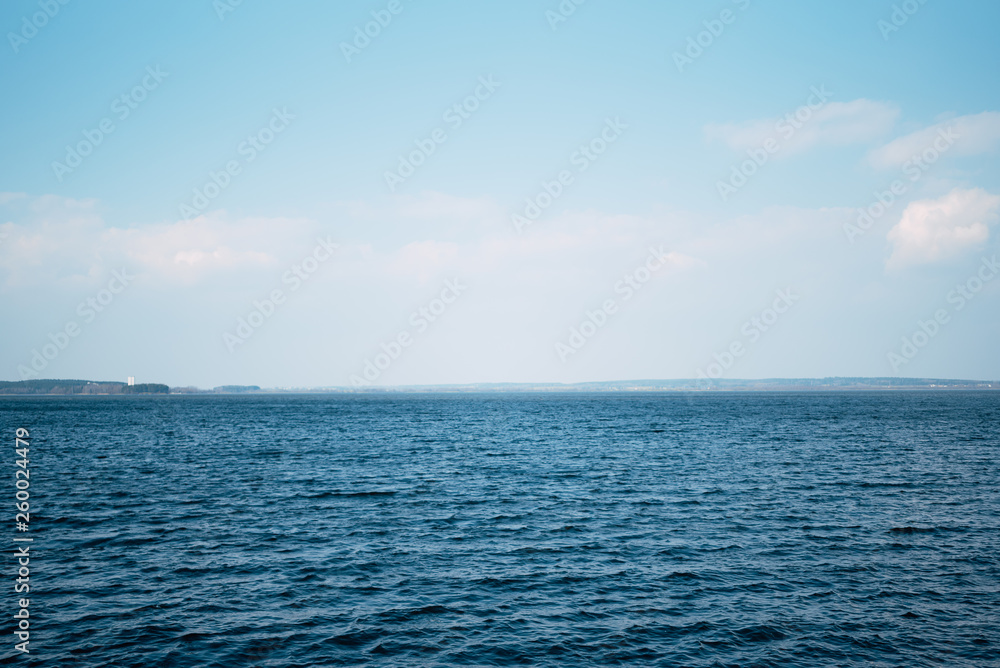 Obraz premium Beautiful deep blue sea, calm sea harmony of the water surface. Sunny sky and incredible lake. Live ocean with clouds on the horizon