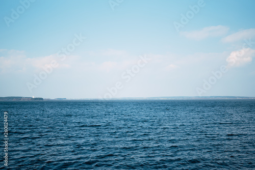 Beautiful deep blue sea, calm sea harmony of the water surface. Sunny sky and incredible lake. Live ocean with clouds on the horizon