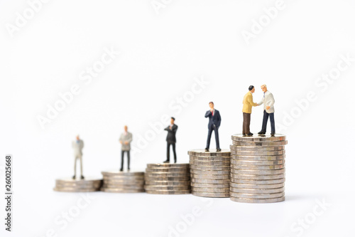 Miniature people, business man standing on stack of coins. Invesment, financial, and savings concept.