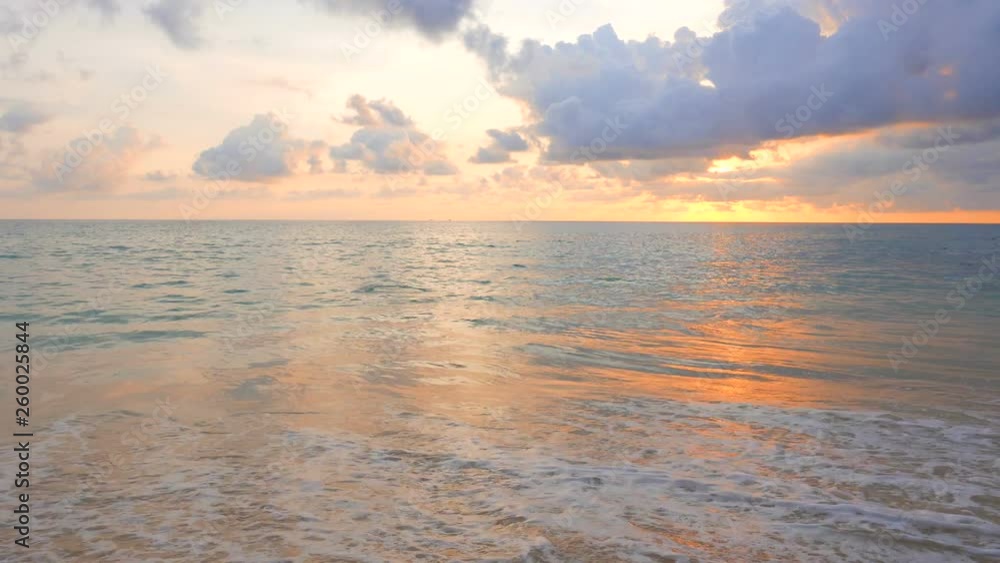 Turquoise water sea wave breaking on shore in tropical beach on colorful sunset with clouds Turquoise water sea wave breaking on shore in tropical beach on colorful sunset with clouds