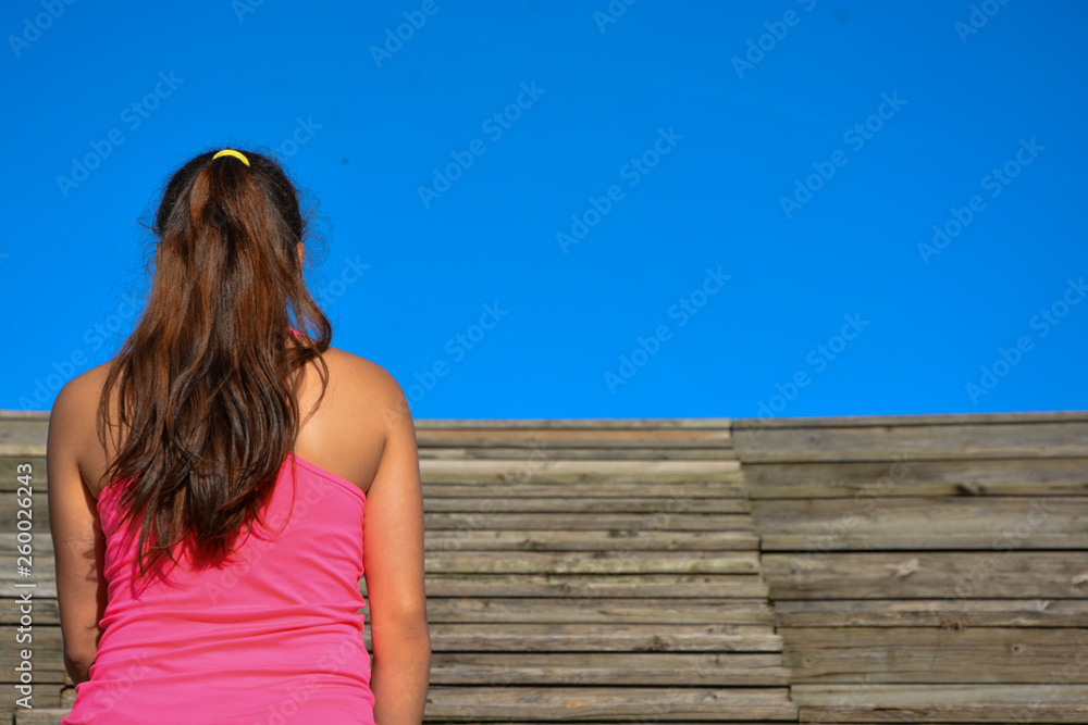 Mujer de espaldas, mirando al cielo en gradas de madera, con espacio libre  foto de Stock | Adobe Stock