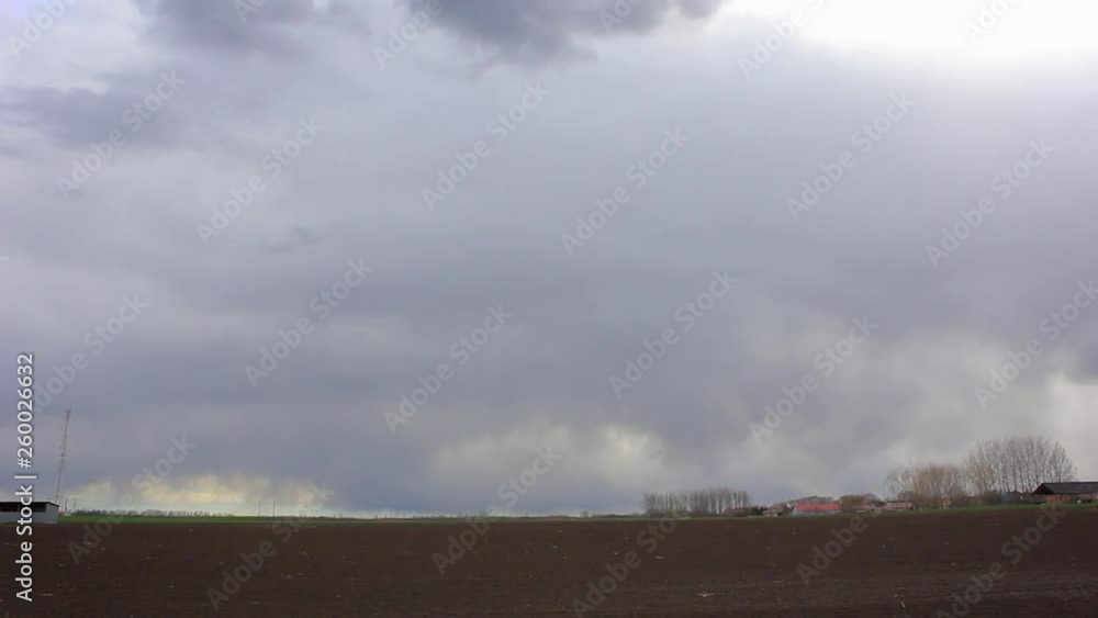 Timelapse of a gloomy, cloudy day above the field. Snow is falling in the distance. Timelapse of a gloomy, cloudy day above the field. Snow is falling in the distance.