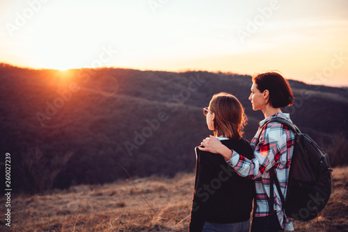 Mother and daughter hiking on a mountain and looking into the sunset
