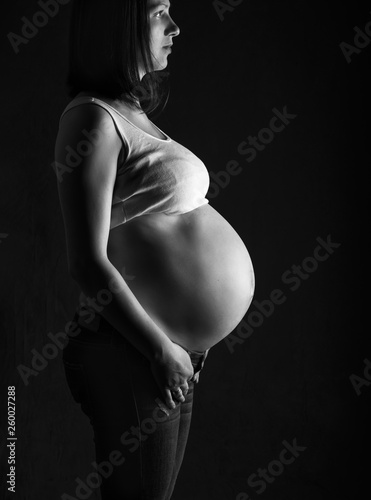 pregnant woman, expectant mother on black background, monoshrome shoot.