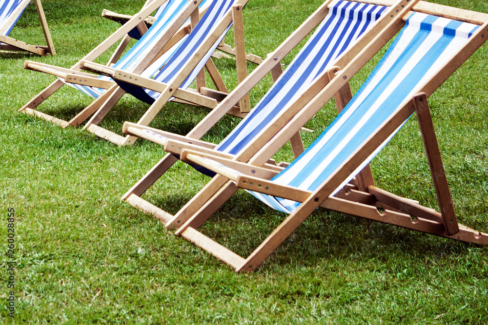 Empty chaise lounges on the green lawn. Summer vacation in the park Empty chaise lounges on the green lawn. Summer vacation in the park